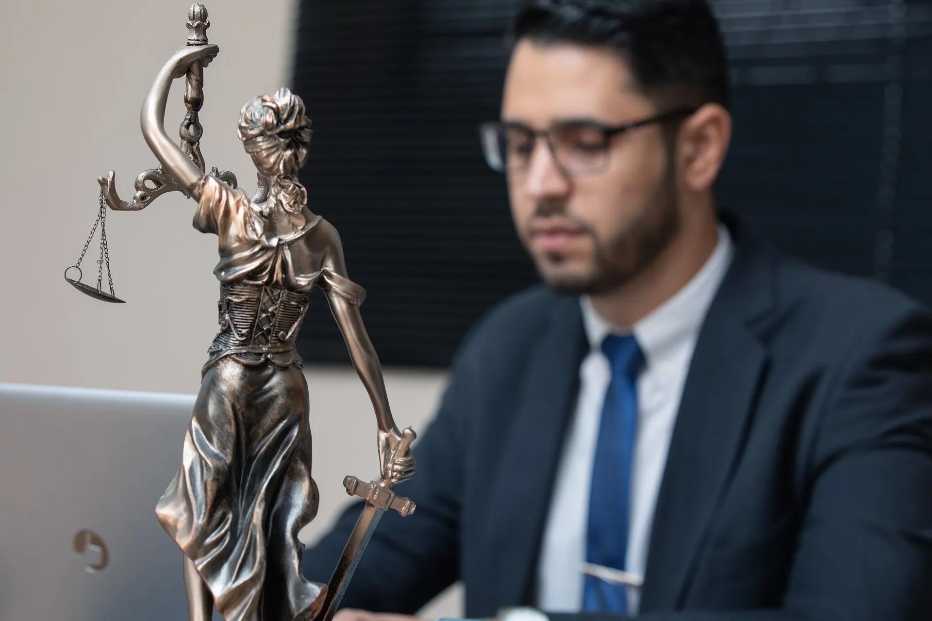 Statue of Lady Justice in the foreground with an attorney working in the background, symbolizing justice and legal representation.