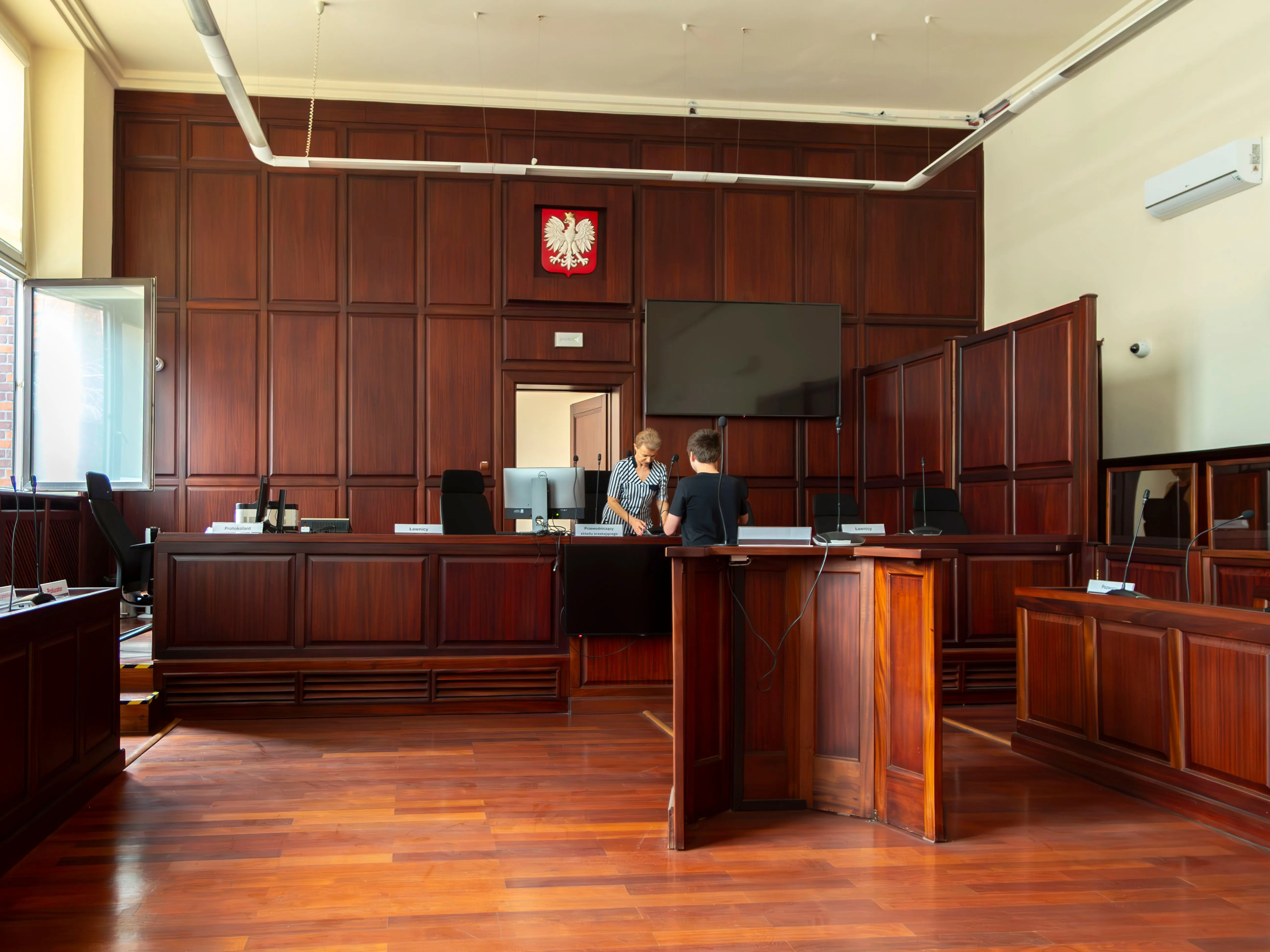 Interior view of an empty courtroom with the judge’s bench, witness stand, and seating prepared for legal proceedings.